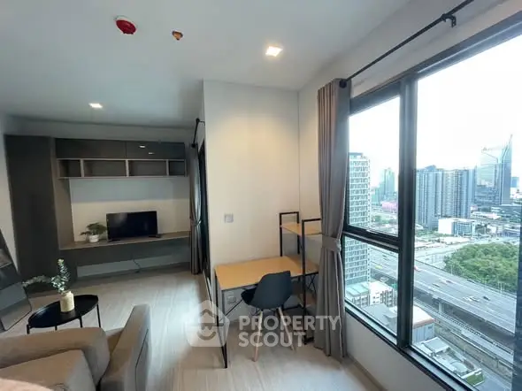 Modern high-rise apartment with city view, featuring a cozy living area and study nook.