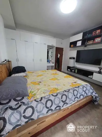 Spacious bedroom with large bed, ample built-in wardrobes, and modern entertainment unit, perfect for relaxation and storage needs.