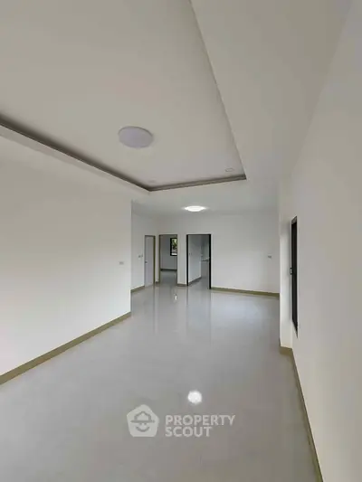 Spacious empty room with modern ceiling design and large windows.