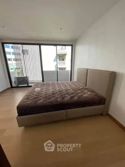 Spacious bedroom with large windows and modern bed in a bright apartment.