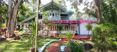 Charming two-story house with lush garden and vibrant floral decorations, perfect for nature lovers seeking tranquility.