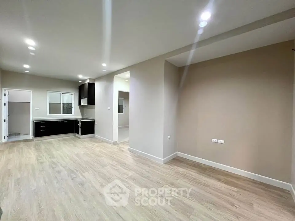 Spacious open-plan living room with modern kitchen and sleek wooden flooring.
