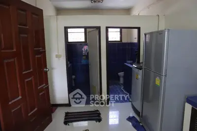 Compact kitchen with fridge and adjacent bathroom in a cozy apartment