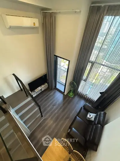 Modern loft apartment with high ceilings and large windows offering stunning city views.
