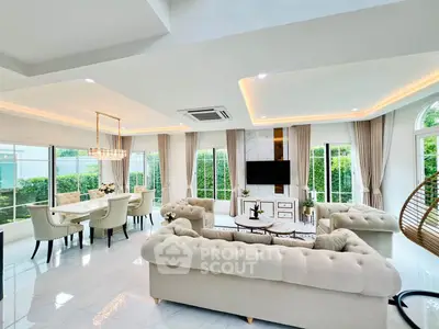 Luxurious open-plan living room with elegant furniture and large windows offering garden views.