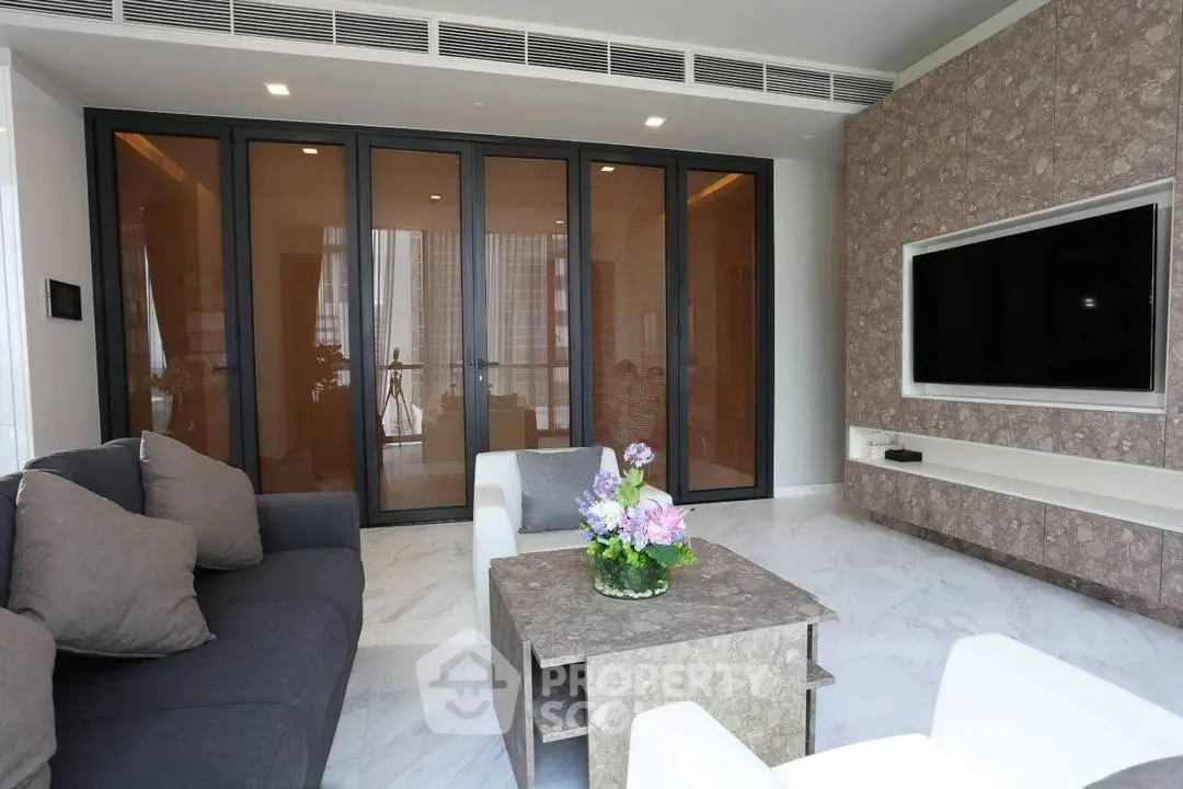 Modern living room with sleek furniture and large TV, featuring elegant marble flooring and stylish decor.