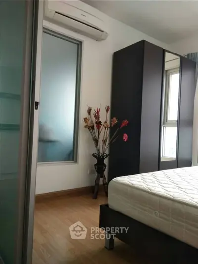 Modern bedroom with wooden flooring, large wardrobe, and air conditioning unit.