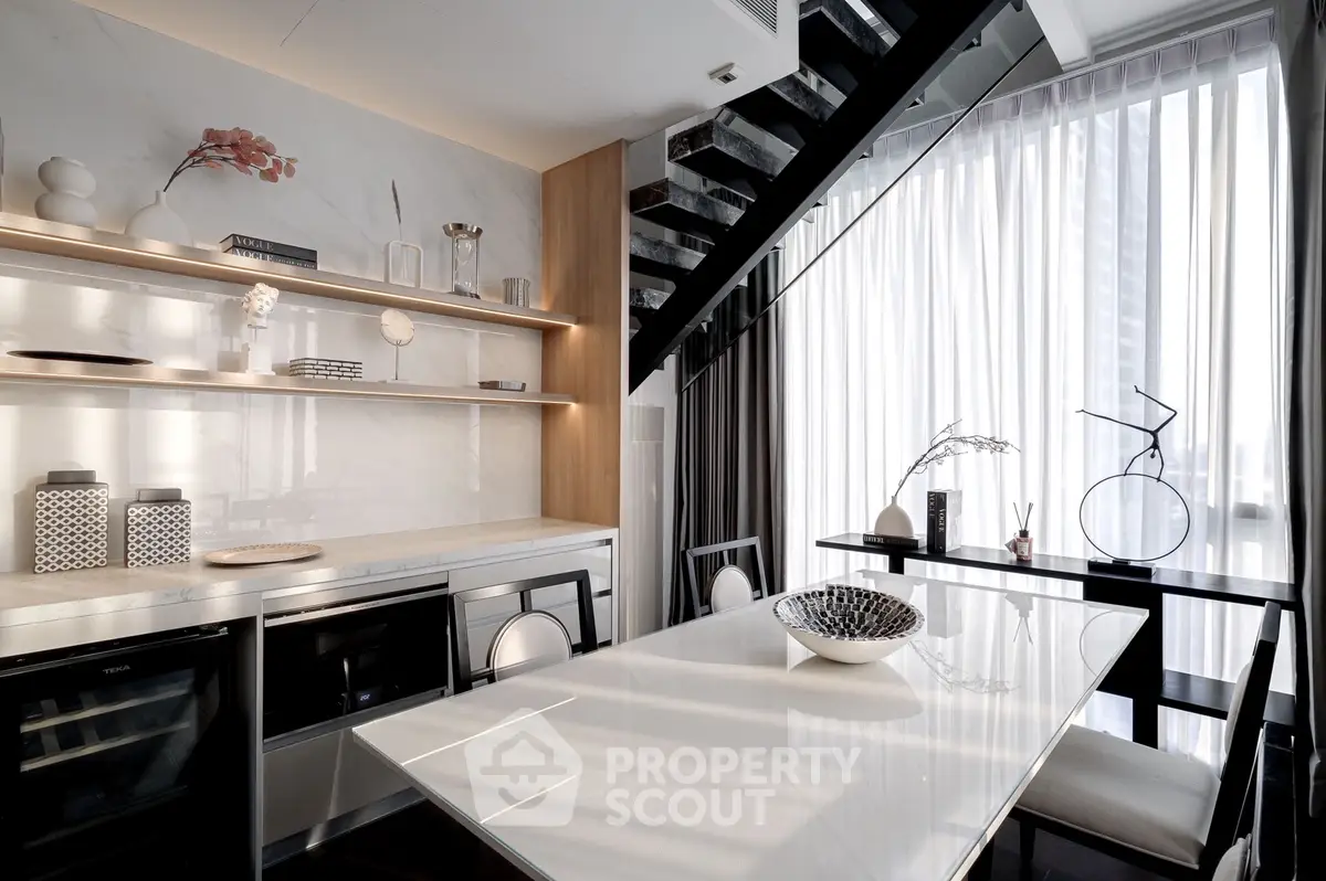 Modern dining area with sleek design and natural light under a staircase