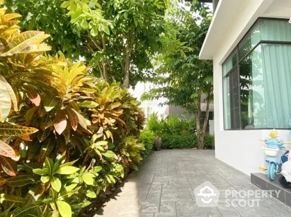 Lush tropical garden adjacent to a modern home with expansive windows and a serene outdoor space, perfect for relaxation and entertaining.