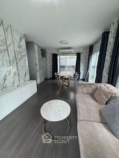 Modern living room with marble accents and elegant furnishings, featuring a cozy sofa and stylish round table.