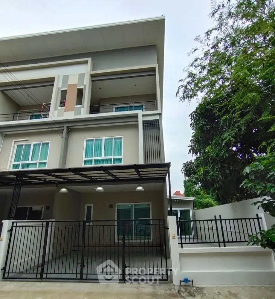 Modern three-story townhouse with sleek design and gated entrance, perfect for urban living.