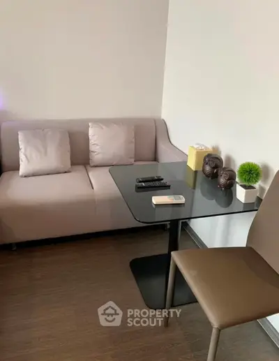 Cozy living room with modern sofa and sleek glass table, perfect for relaxation and entertainment.
