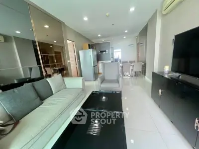 Modern living room with sleek furniture and open kitchen layout in a stylish apartment.