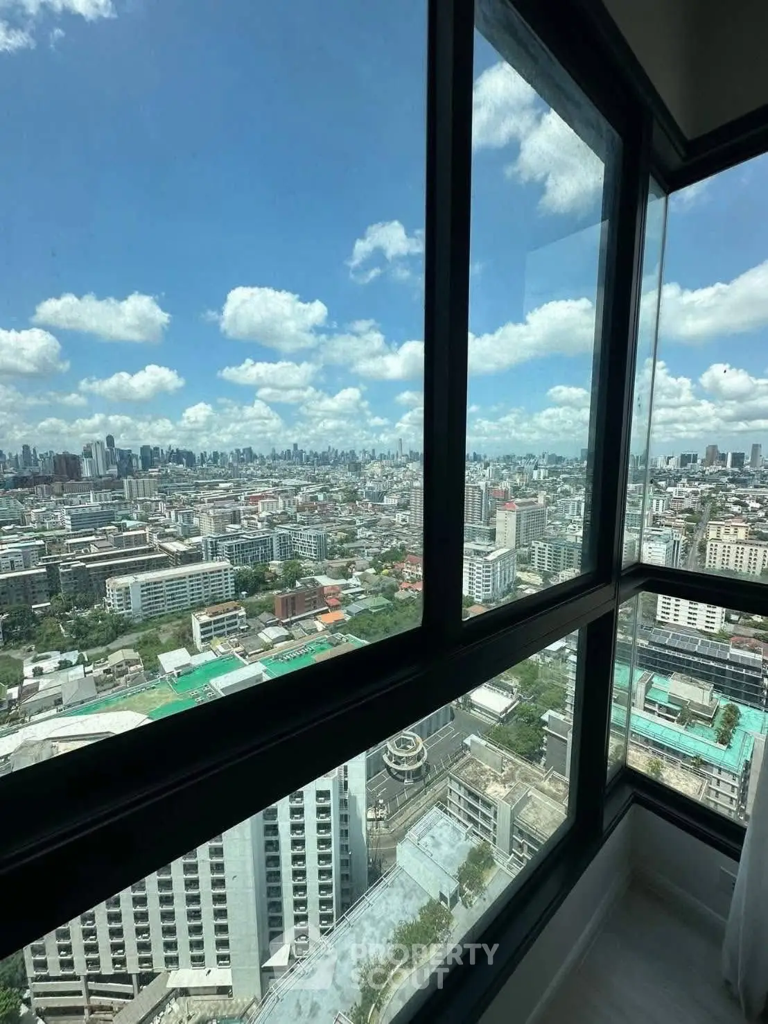 Stunning cityscape view from high-rise apartment window with clear blue skies.