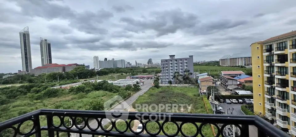 Stunning cityscape view from a balcony with modern high-rise buildings and lush greenery.