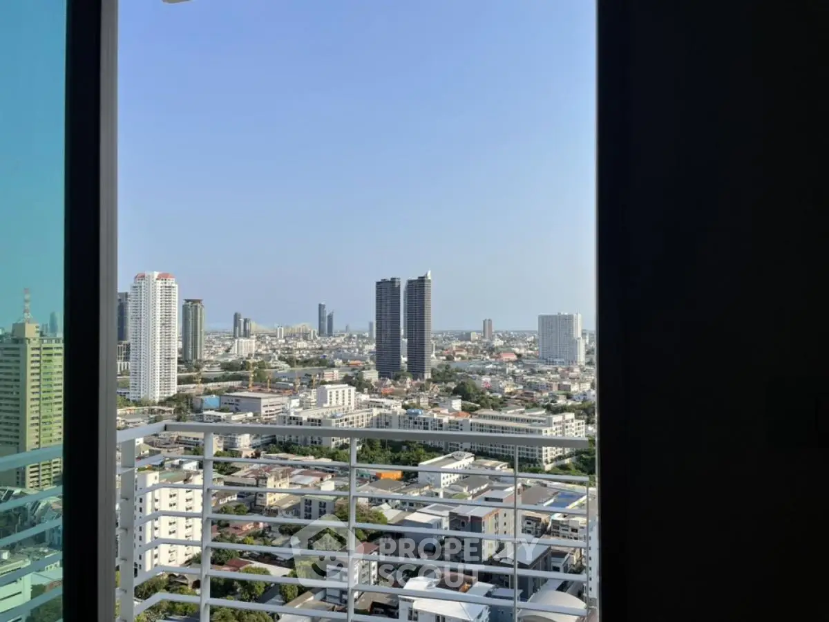 Stunning cityscape view from a high-rise balcony, showcasing urban skyline and clear blue sky.
