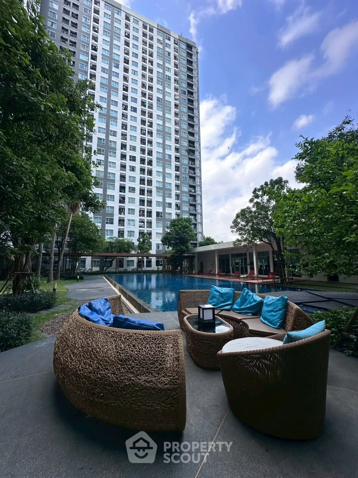 Luxurious high-rise building with poolside seating and lush greenery, perfect for modern urban living.