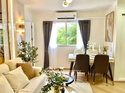 Charming living room with elegant dining area, lush greenery view, and modern decor.