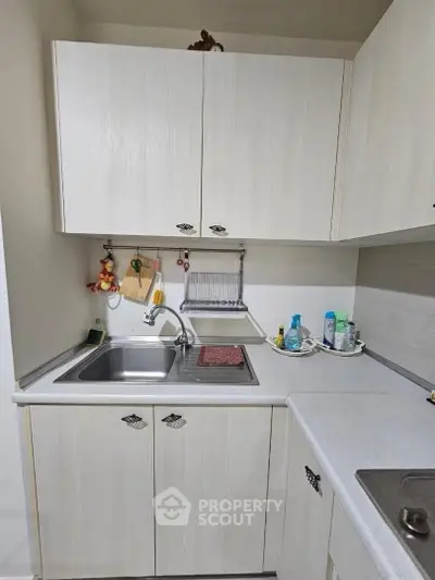 Charming compact kitchen with white cabinetry and modern fixtures, perfect for efficient cooking in a cozy home.