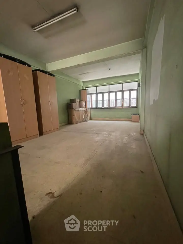 Spacious room with large windows and ample storage in a versatile real estate property.