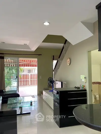 Spacious living room with modern decor and large glass doors leading to a balcony.
