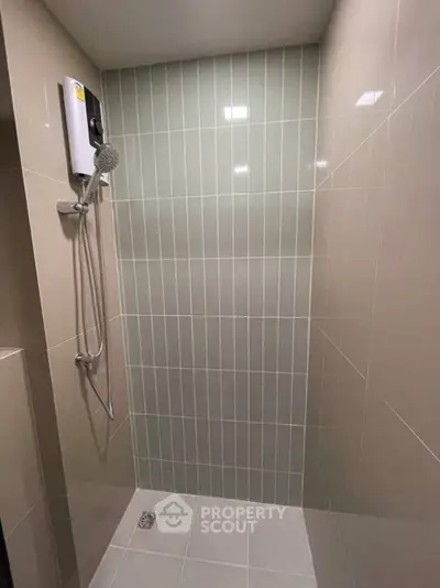 Modern bathroom shower area with sleek tile design and wall-mounted showerhead.