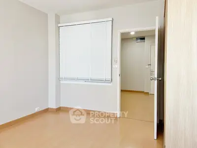 Spacious empty room with wooden flooring and white blinds, perfect for customization.