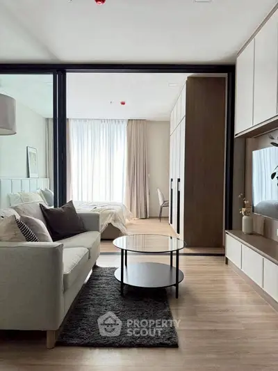 Modern living room with cozy sofa and stylish decor leading to a bright bedroom.