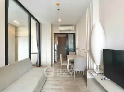 Modern living room with sleek furniture and neutral tones, featuring a TV and dining area.