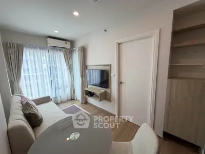 Modern living room with cozy sofa, wall-mounted TV, and natural light from large window.
