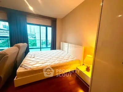 Cozy bedroom with large window and city view, featuring a comfortable bed and warm lighting.