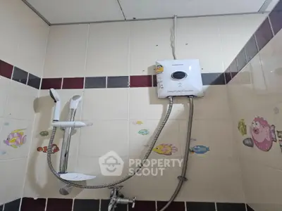 Compact bathroom with shower and water heater, featuring playful fish-themed wall tiles.