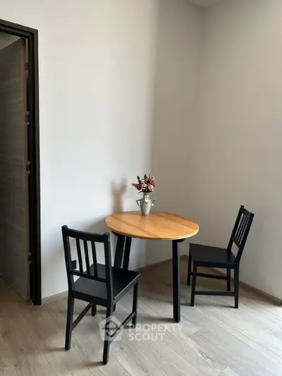 Cozy dining nook with round wooden table and two chairs in modern apartment.