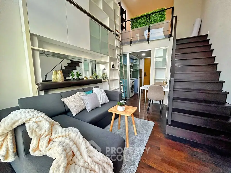 Modern loft apartment with stylish living area and mezzanine, featuring sleek furniture and open layout.