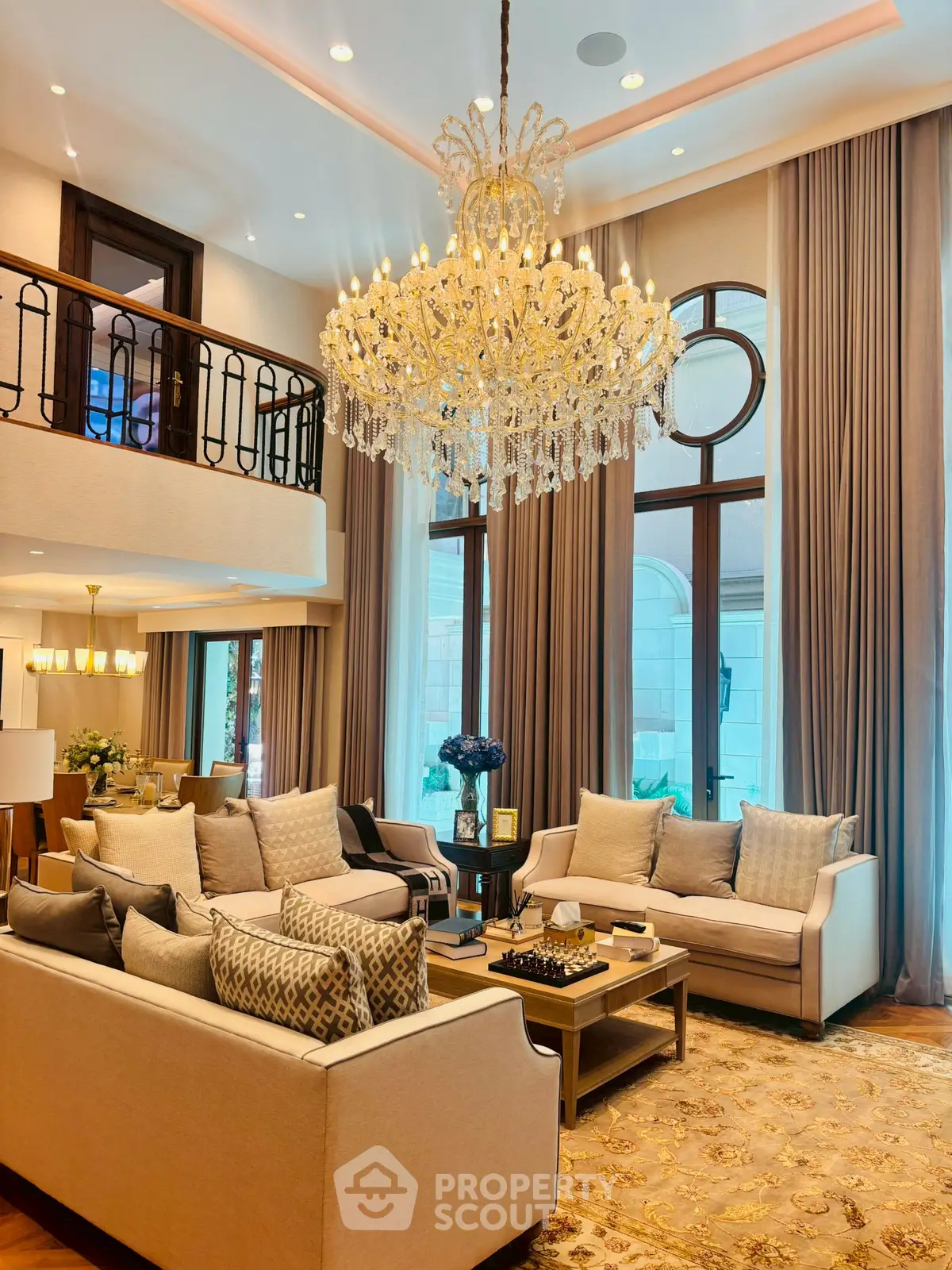 Luxurious living room with elegant chandelier and plush seating in a high-ceilinged space.