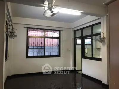 Spacious room with large windows and ceiling fan, ideal for versatile living space.