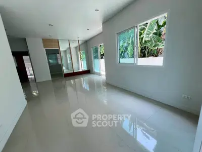 Spacious living room with large windows and garden view, perfect for natural light lovers.