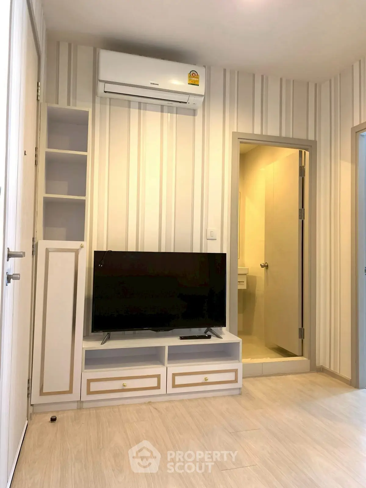 Modern living room with air conditioning and TV unit, adjacent to a bathroom.