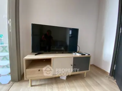 Modern living room with sleek TV stand and flat-screen TV, showcasing minimalist design and wooden flooring.