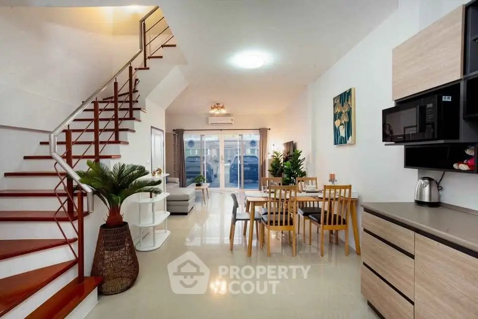 Spacious modern living room with open kitchen and elegant staircase, perfect for family gatherings.