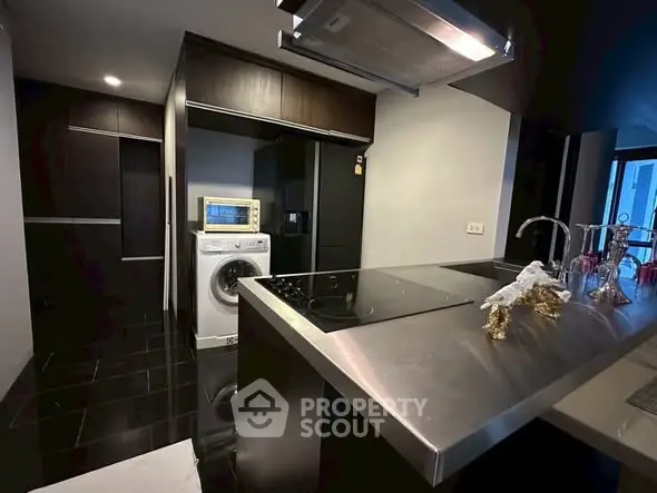 Modern kitchen with sleek appliances and washing machine in stylish apartment.