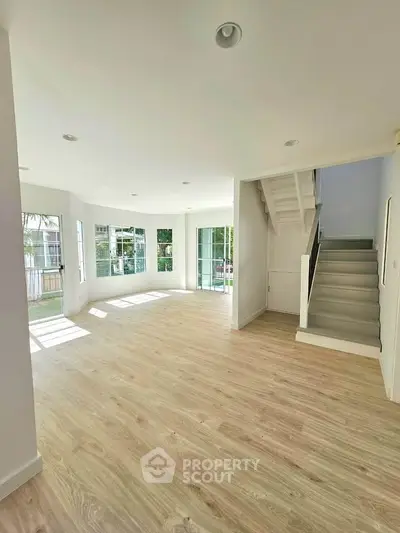 Spacious bright living room with wooden flooring and staircase in modern home