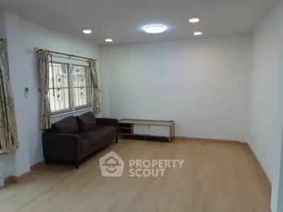 Spacious living room with wooden flooring and cozy sofa, perfect for relaxation.