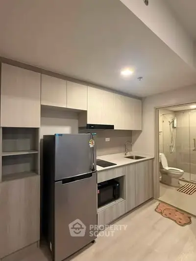 Modern kitchen with sleek cabinetry and stainless steel appliances in a compact apartment setting.
