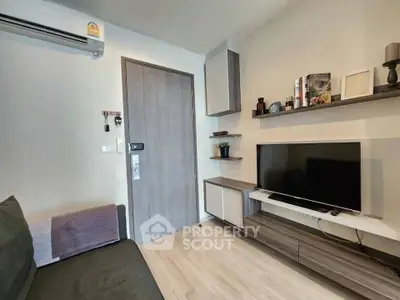 Modern living room with sleek furniture and wall-mounted TV in a cozy apartment.