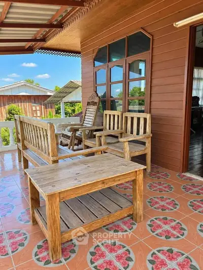 Charming wooden patio with rustic furniture and floral tile flooring, perfect for relaxing outdoors.