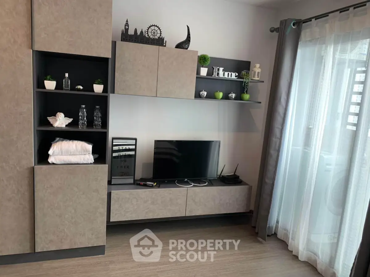 Modern living room with stylish shelving and TV unit, featuring decorative accents and natural light.