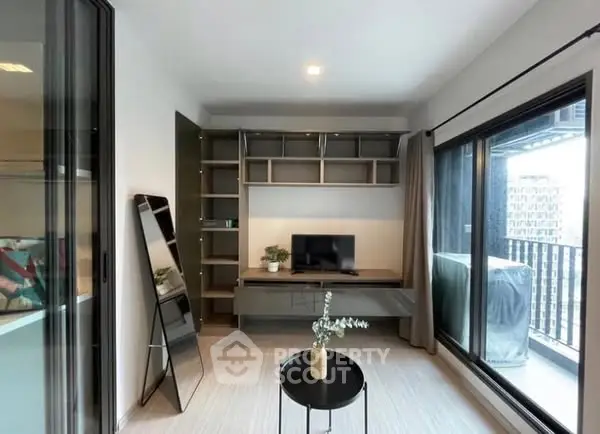 Modern living room with sleek furniture and large windows opening to a balcony.