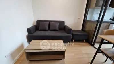 Modern living room with sleek sofa and wooden coffee table, open kitchen view.