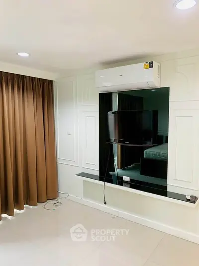 Modern living room with air conditioning and wall-mounted TV, featuring elegant curtains and sleek flooring.